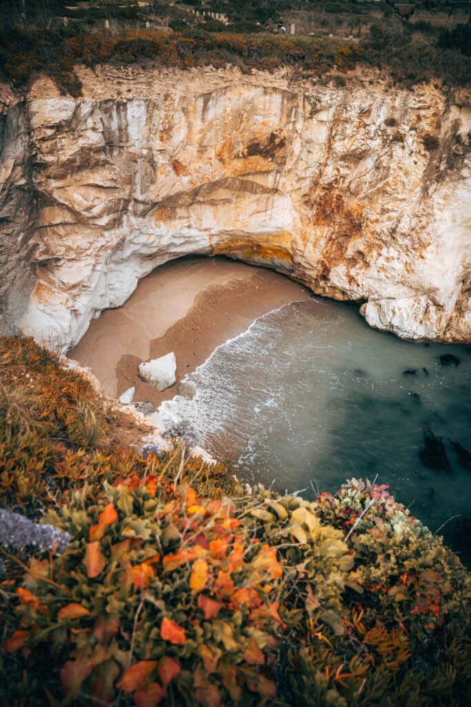 A secluded beach cove framed by rocky cliffs along the California coast