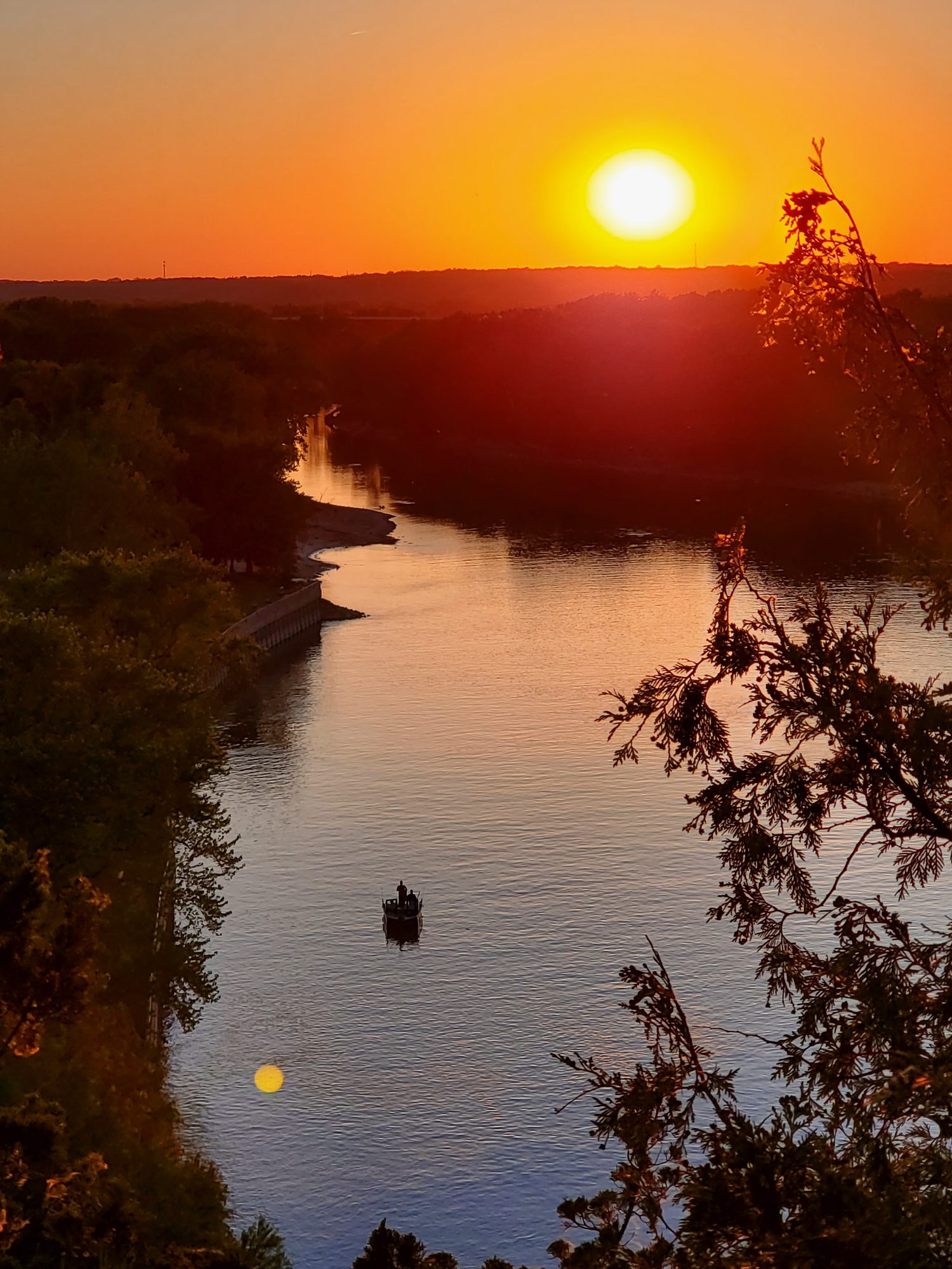 Sun setting over the Illinois River at Starved Rock with a lone fishing boat mid-river