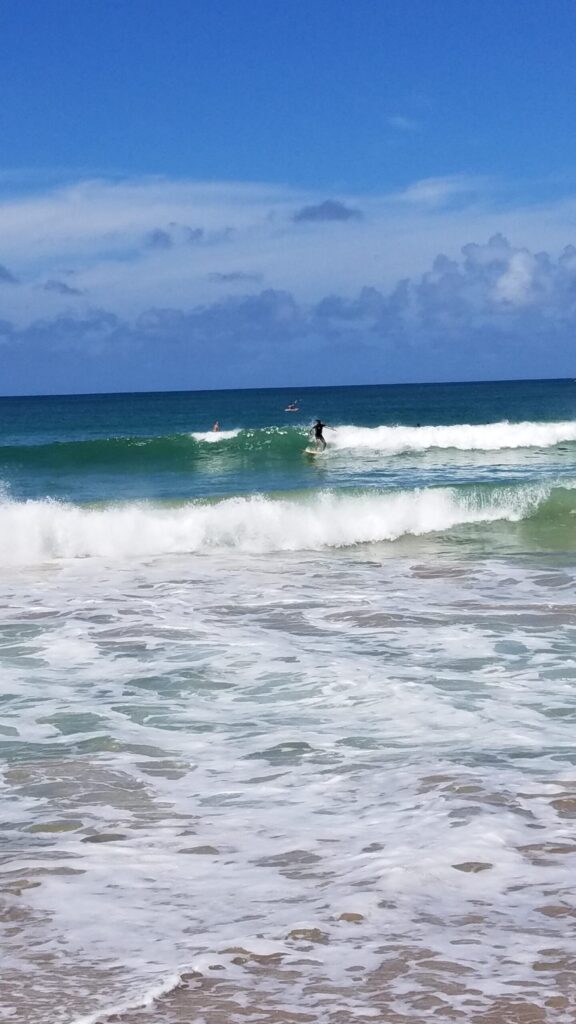 Surfer catching a wave off a Kauai beach