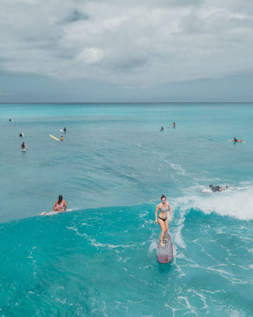 Surfers riding waves in turquoise water off the Honolulu coastline
