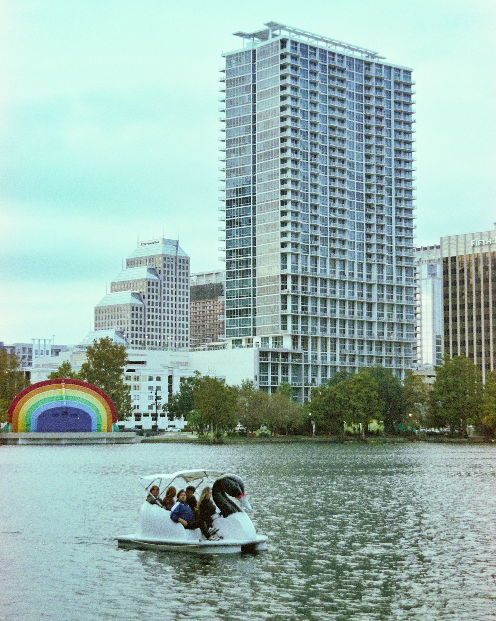 A swan-shaped pedal boat on Lake Eola with the downtown Orlando skyline behind it