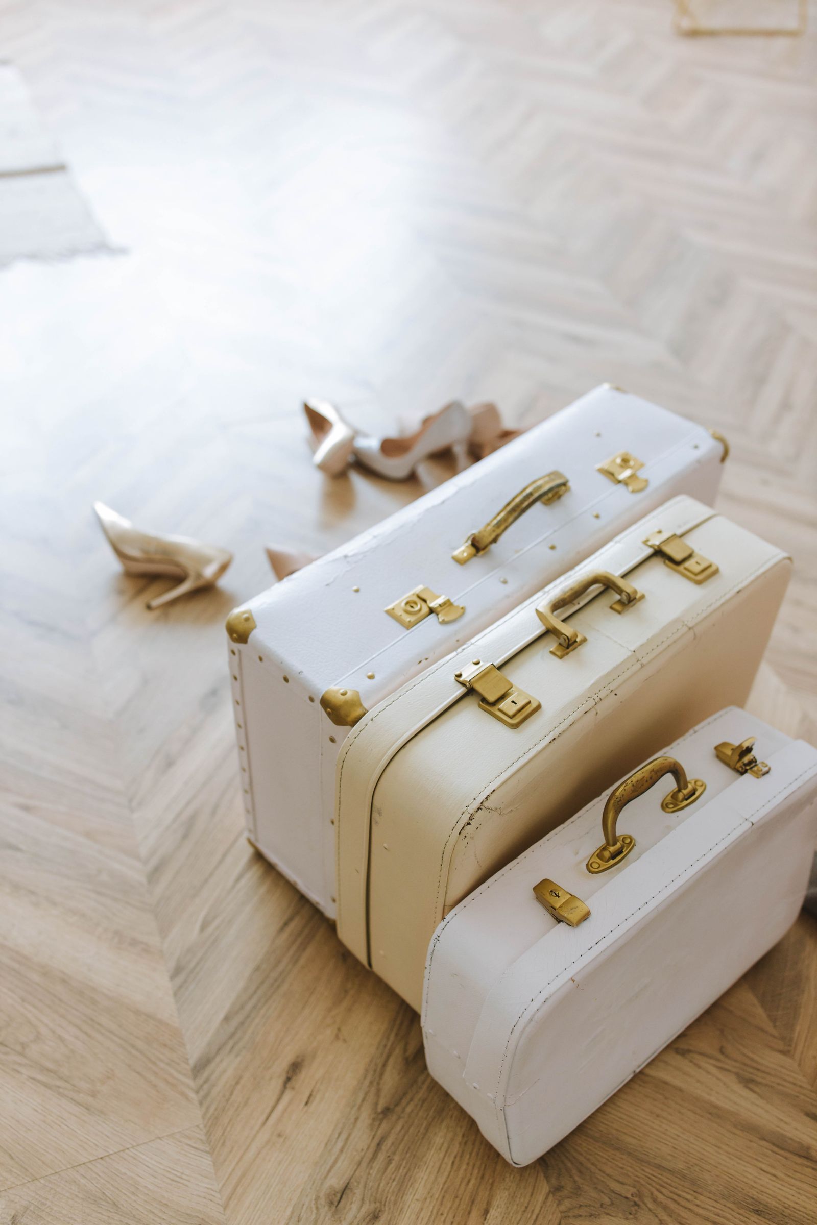 Three vintage suitcases of different sizes stacked on a wood floor