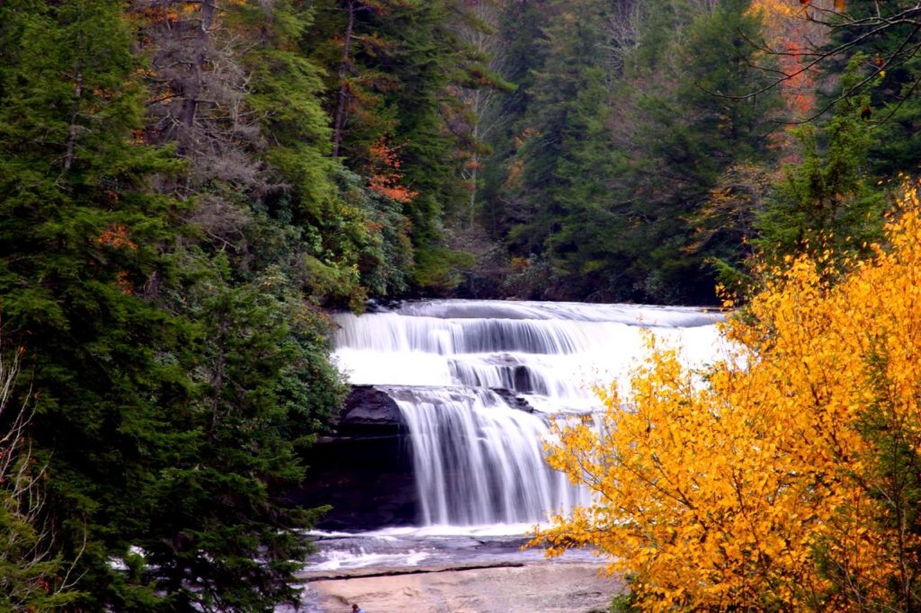 Triple Falls, a multi-tiered waterfall in DuPont State Forest near Asheville, with fall foliage on the banks