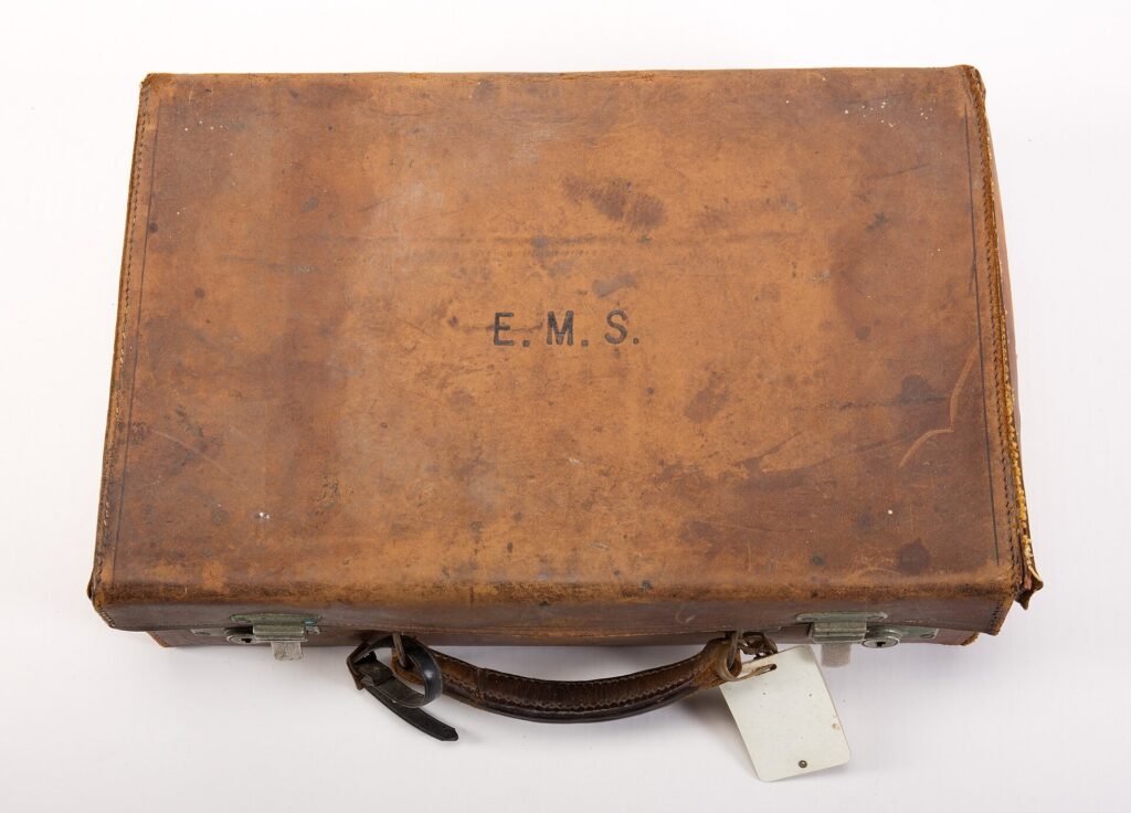 A vintage leather suitcase photographed against a plain background