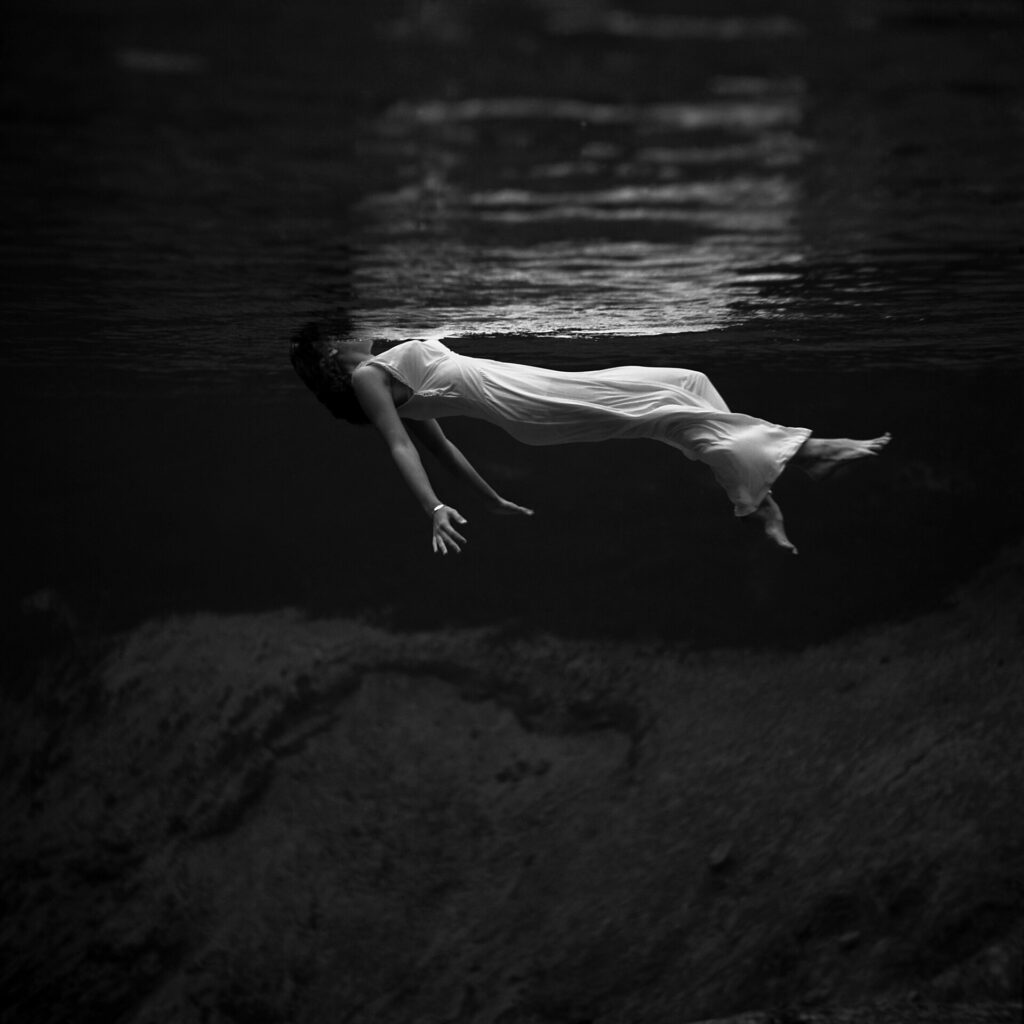 A woman in a flowing white gown floats underwater at Weeki Wachee Springs in a 1940s-era photo