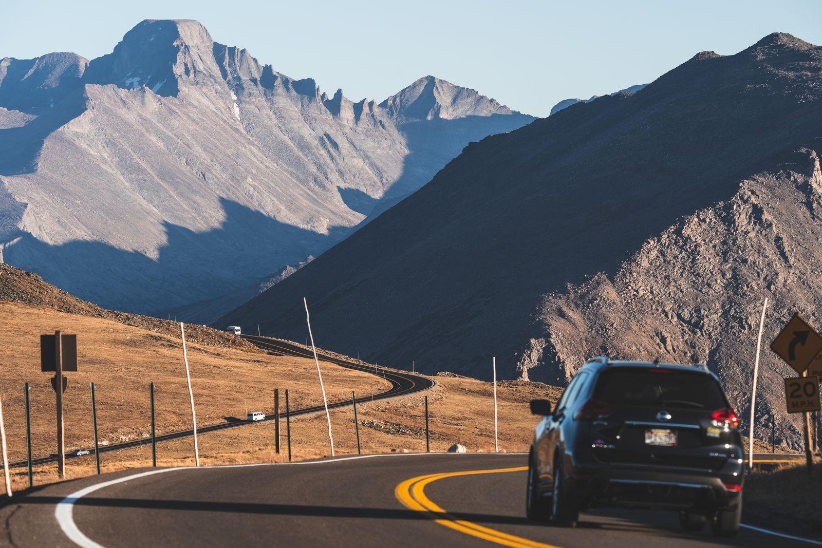 A car drives a winding mountain road above the treeline near Estes Park, Colorado