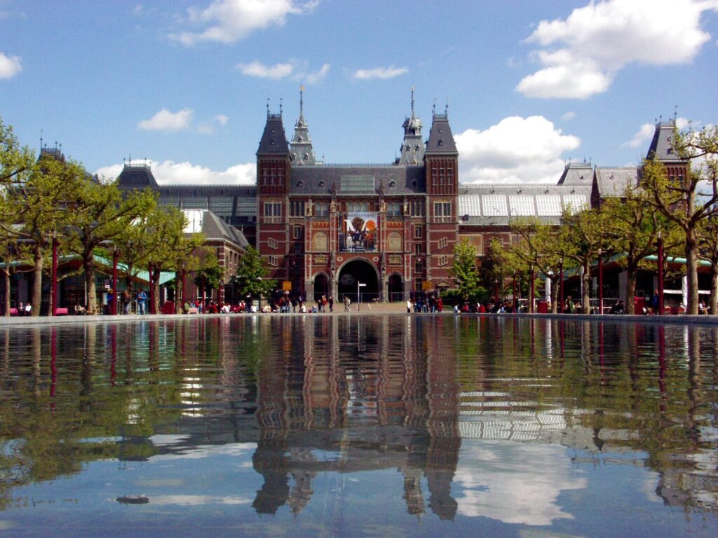 Brick facade and towers of the Rijksmuseum reflected in a pool in Amsterdam