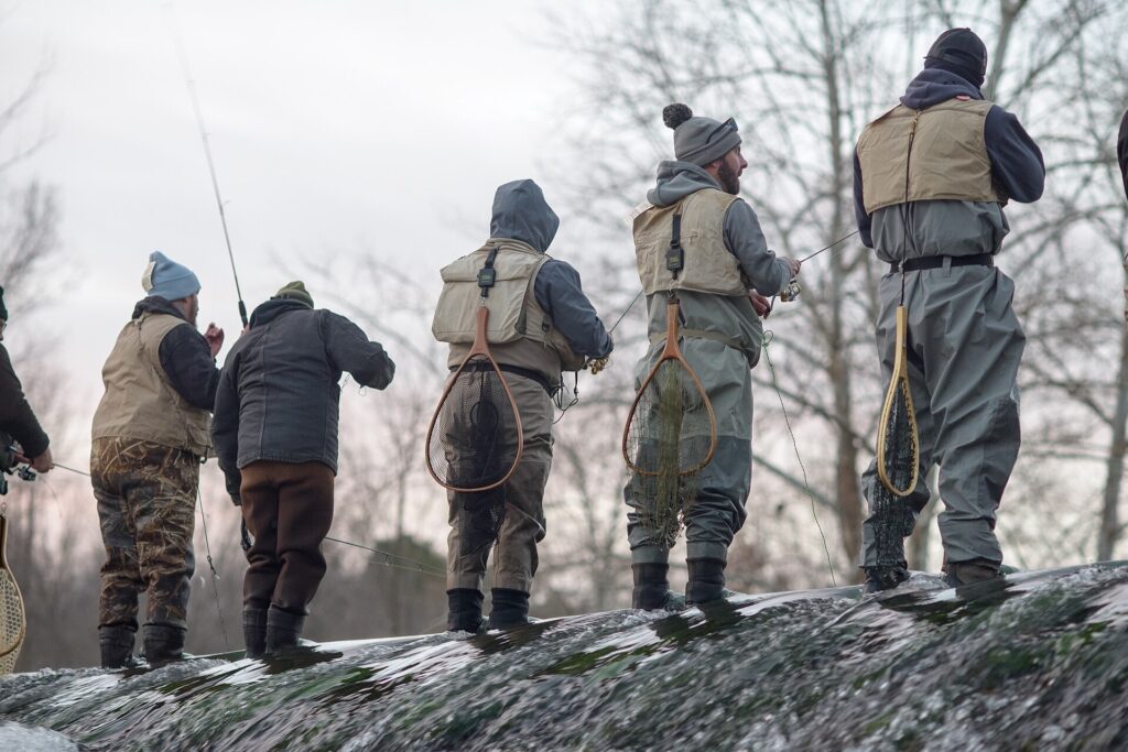 Anglers in waders lined up along the dam at Bennett Spring State Park, Missouri