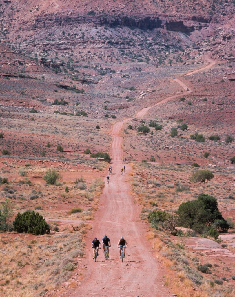 Cyclists riding the dirt White Rim Road below the mesa at Island in the Sky, Canyonlands