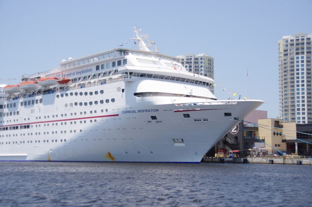 Carnival Inspiration cruise ship docked at the Port of Tampa with downtown towers behind it