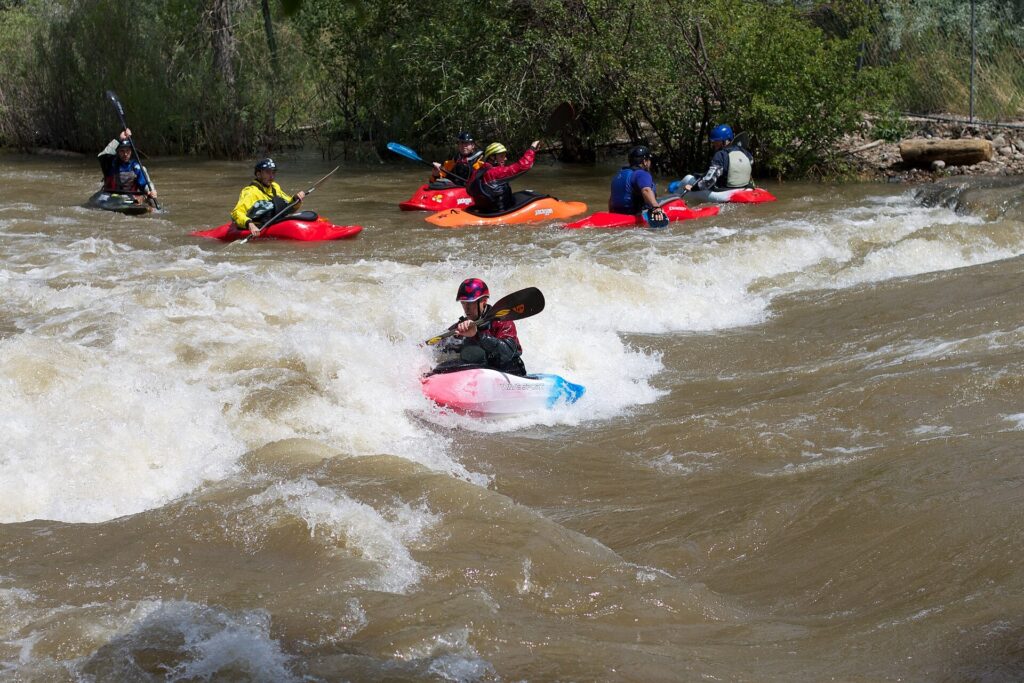 Kayakers working a whitewater wave on Clear Creek in Colorado