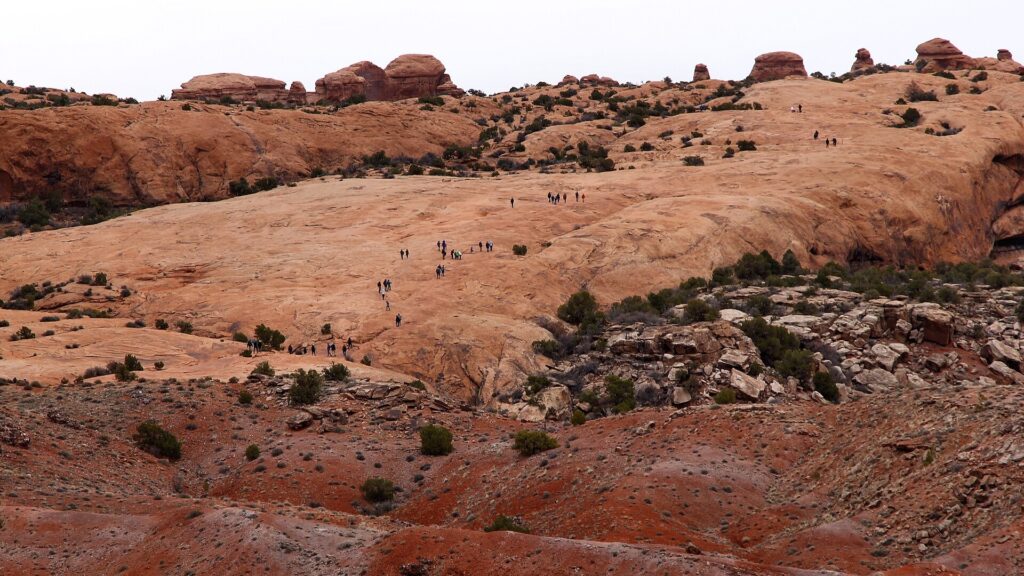 Hikers crossing bare slickrock on the Delicate Arch Trail in Arches National Park