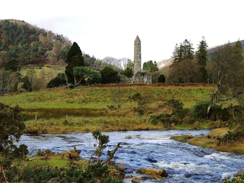 Round tower above the valley floor with a stream in the foreground at Glendalough in County Wicklow