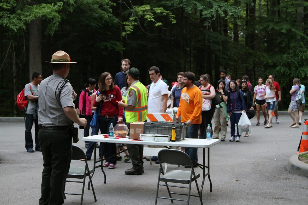 Park rangers and visitors gathered around a check-in table at a Great Smoky Mountains firefly viewing event