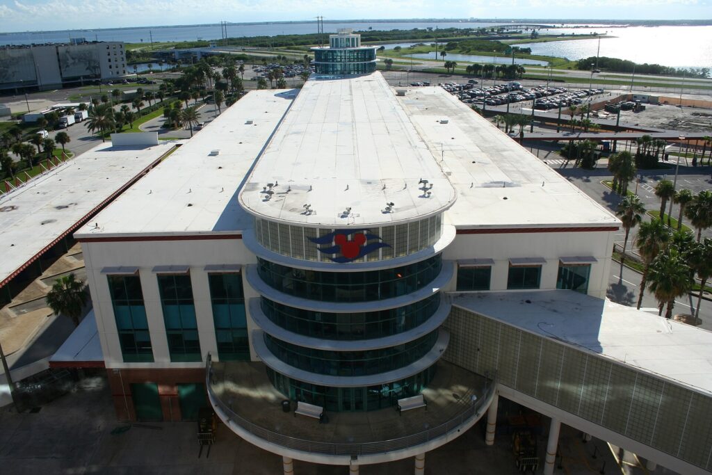 A cruise terminal building at Port Canaveral, Florida, seen from above with parking lots and shoreline beyond