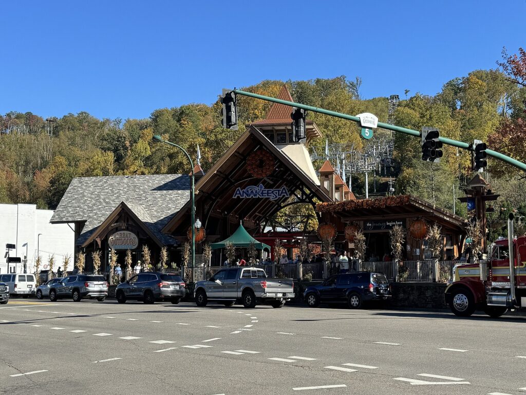 Timber-framed Anakeesta entrance on the street in downtown Gatlinburg with parked trucks in front