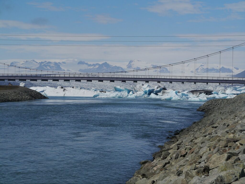 Icebergs drifting beside a road bridge at Jökulsárlón glacier lagoon in southern Iceland
