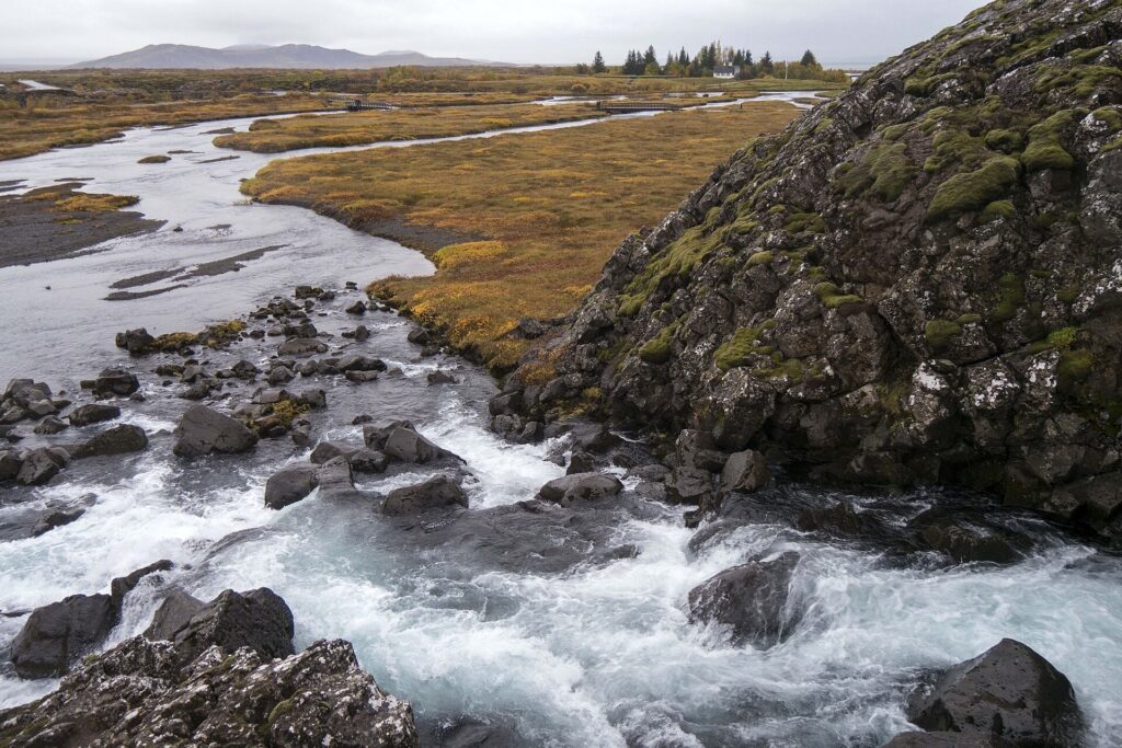 A glacial river running over dark lava rock across the Þingvellir plain in Iceland