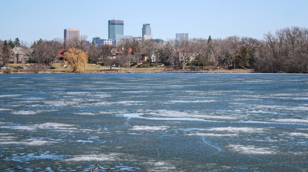 Lake of the Isles in Minneapolis with ice forming on the water and the downtown skyline beyond