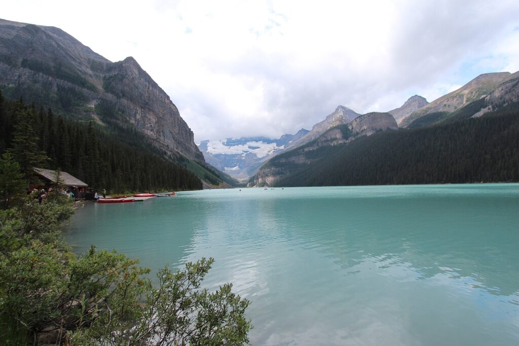 Red canoes tied at a dock on the turquoise water of Lake Louise with mountains behind