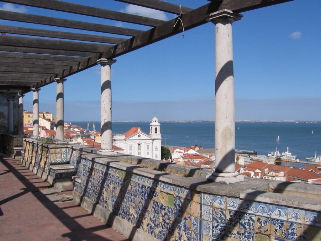 Tiled wall and pergola at Miradouro de Santa Luzia in Alfama, Lisbon, looking over rooftops to the river