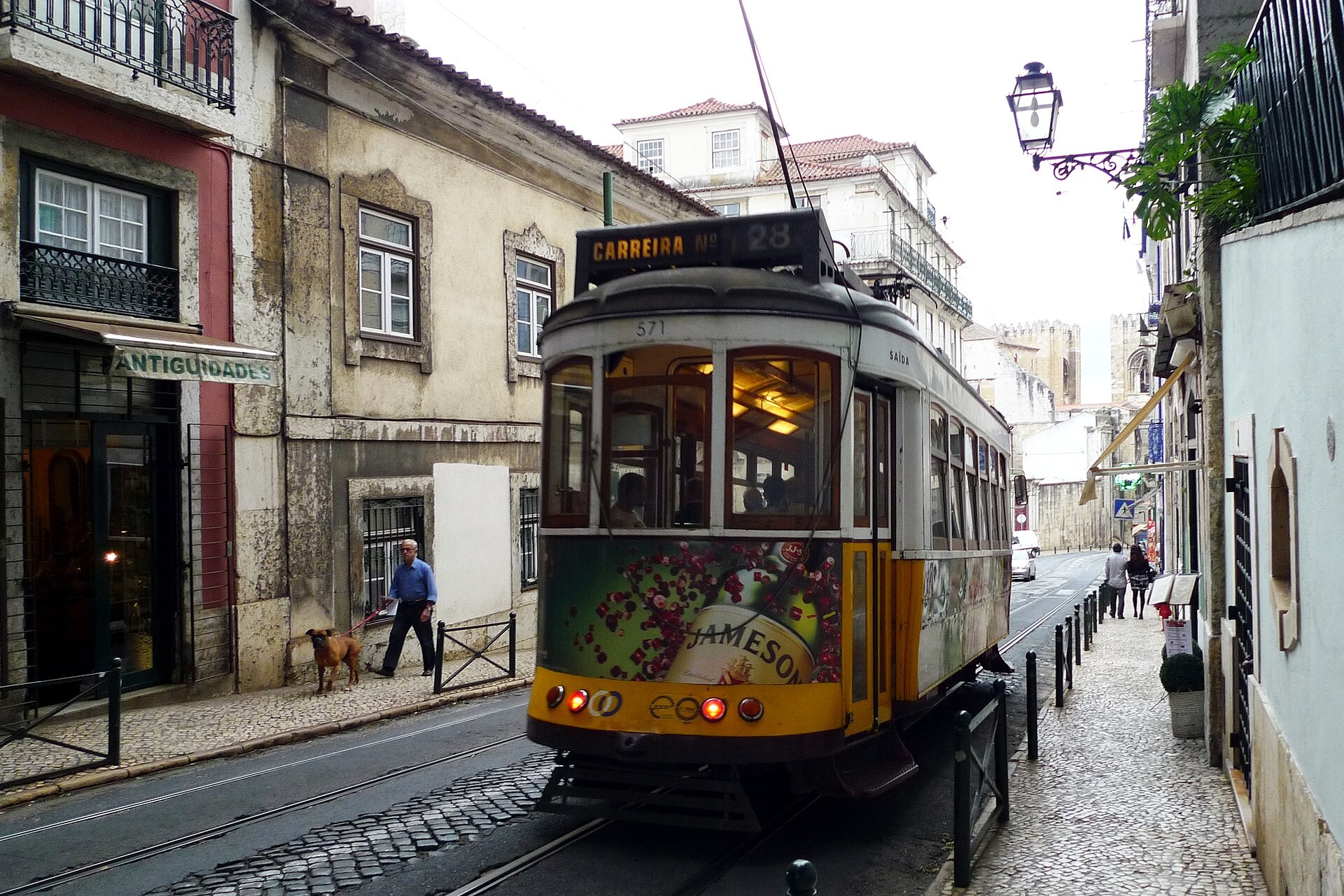 Yellow Tram 28 on a narrow cobbled street in the Alfama district of Lisbon