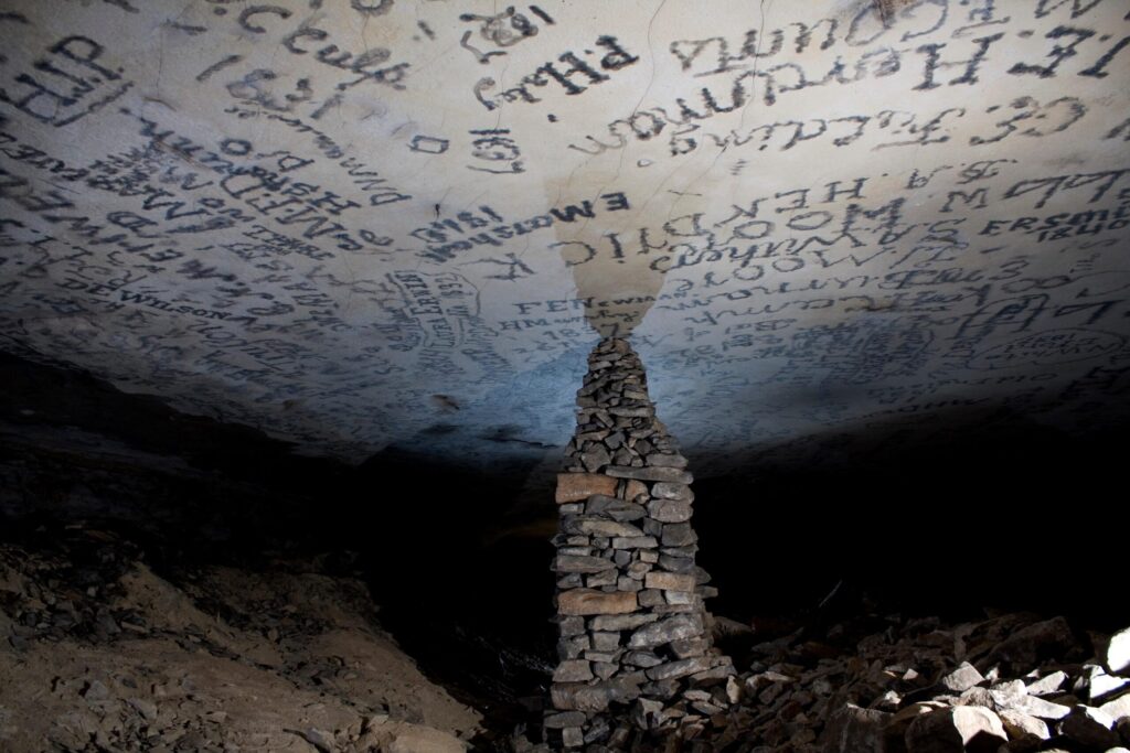 Names written across the ceiling above a stacked-rock pillar on Gothic Avenue, Mammoth Cave