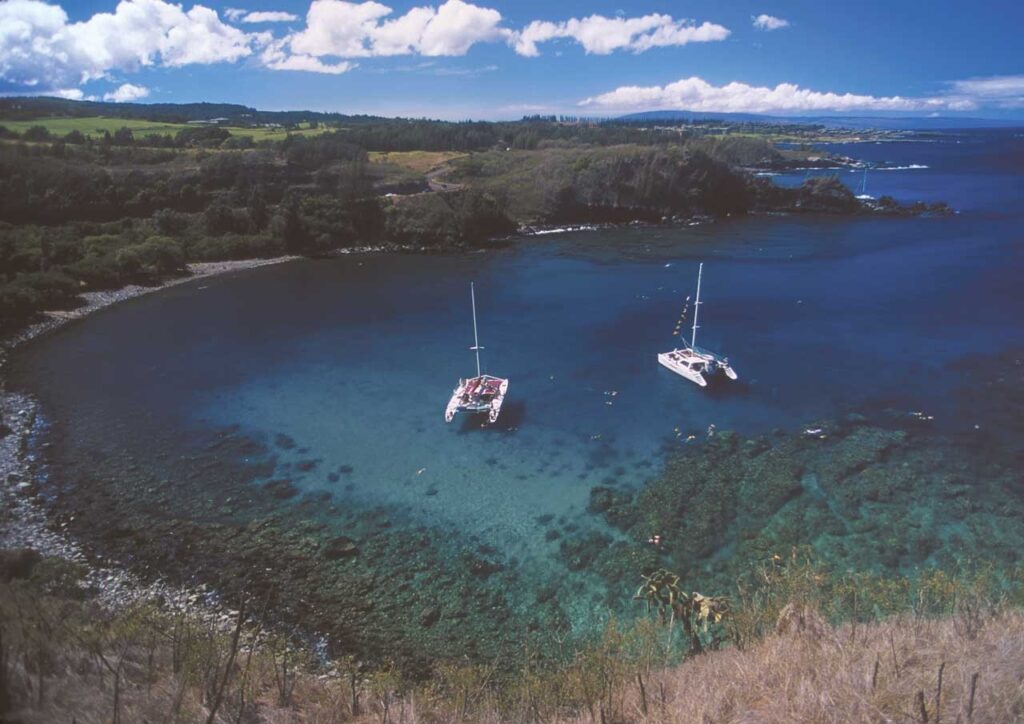 Honolua Bay on Maui seen from the road above, with two sailboats in the water