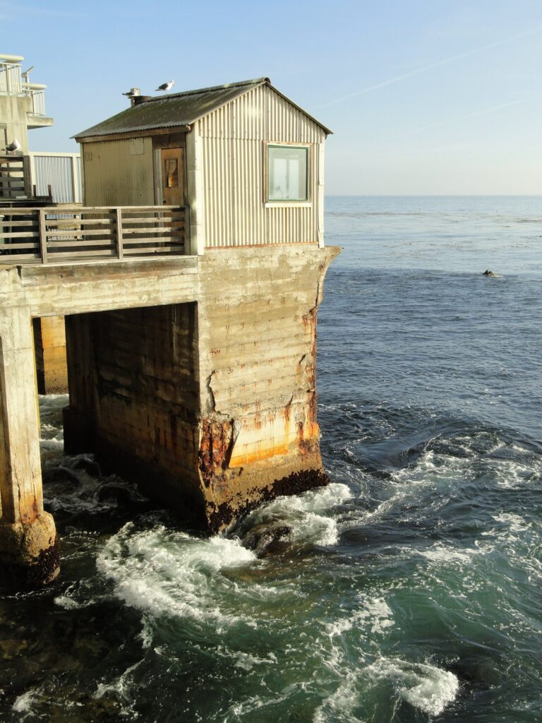 A weathered building on pilings above the surf on Cannery Row in Monterey