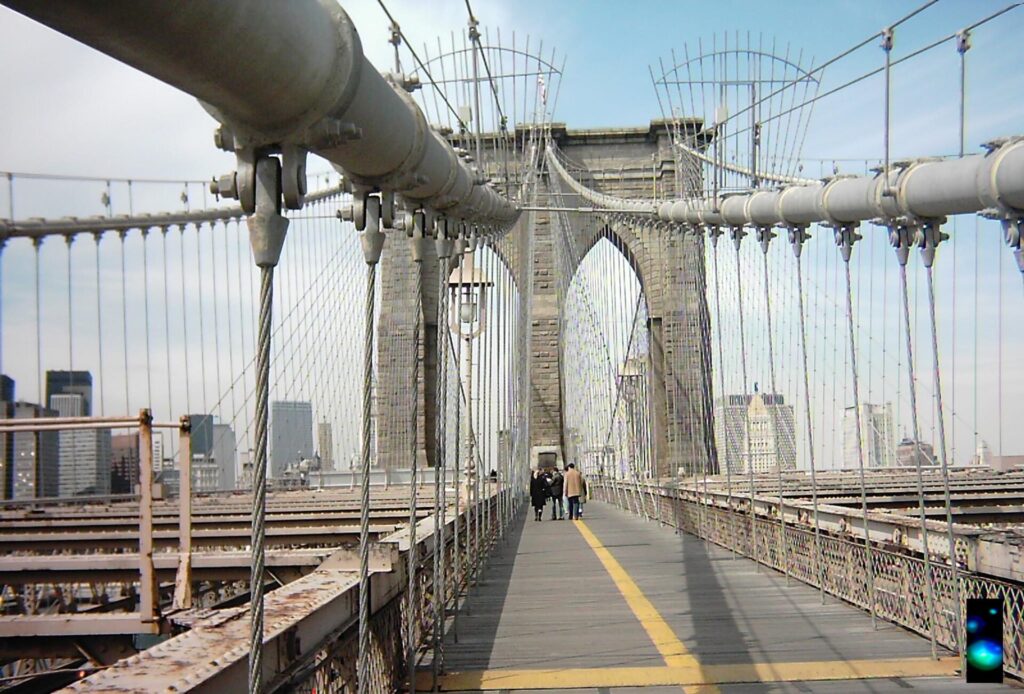 The Brooklyn Bridge stone tower and steel cables seen from the pedestrian walkway