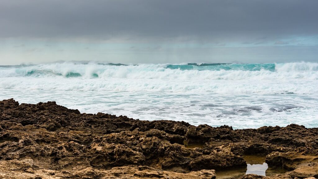 Large winter swell breaking over a reef and rocky shoreline off the Oahu North Shore