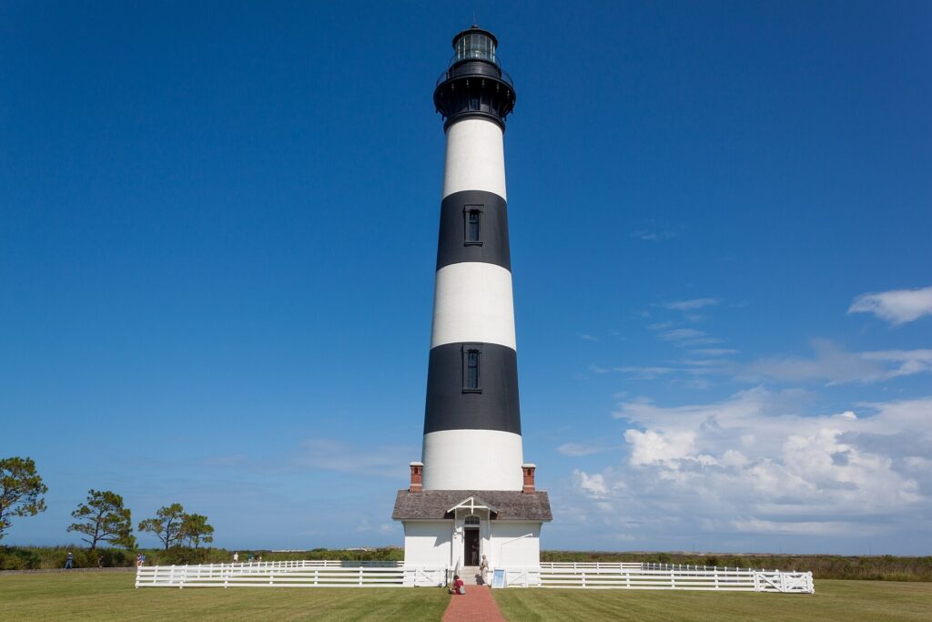 Black-and-white striped Bodie Island Lighthouse standing above grass and trees on the Outer Banks, North Carolina