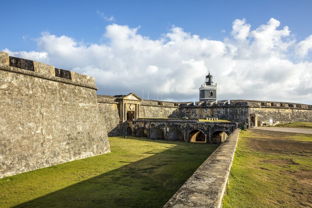 Stone walls, a grassy courtyard and the lighthouse of Castillo San Felipe del Morro in San Juan, Puerto Rico