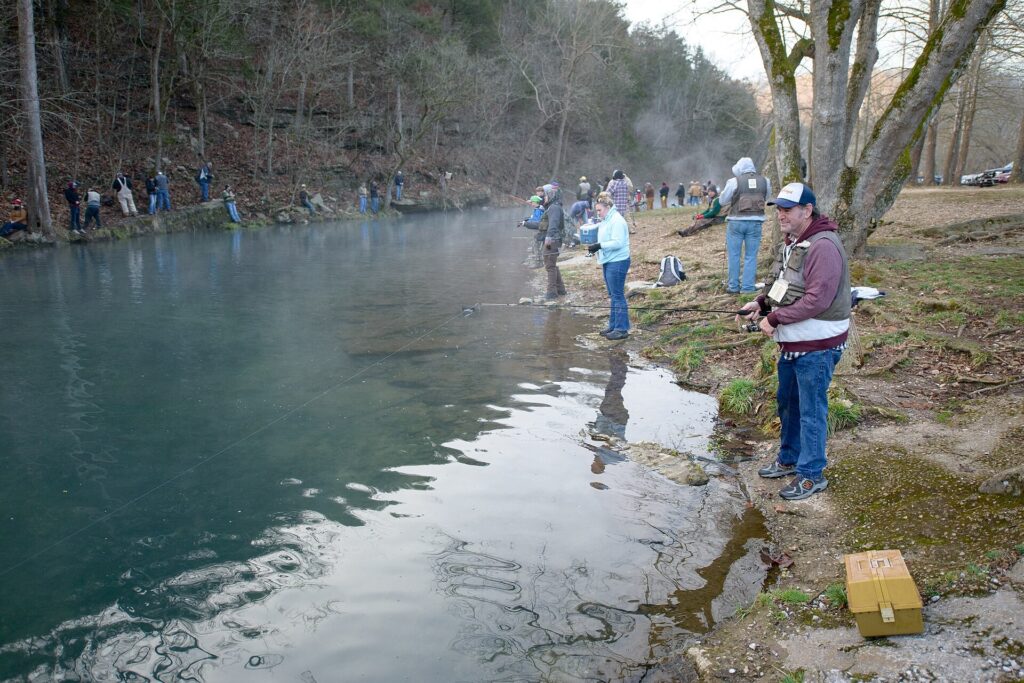 Anglers standing along the blue-green water of Roaring River in Roaring River State Park, Missouri
