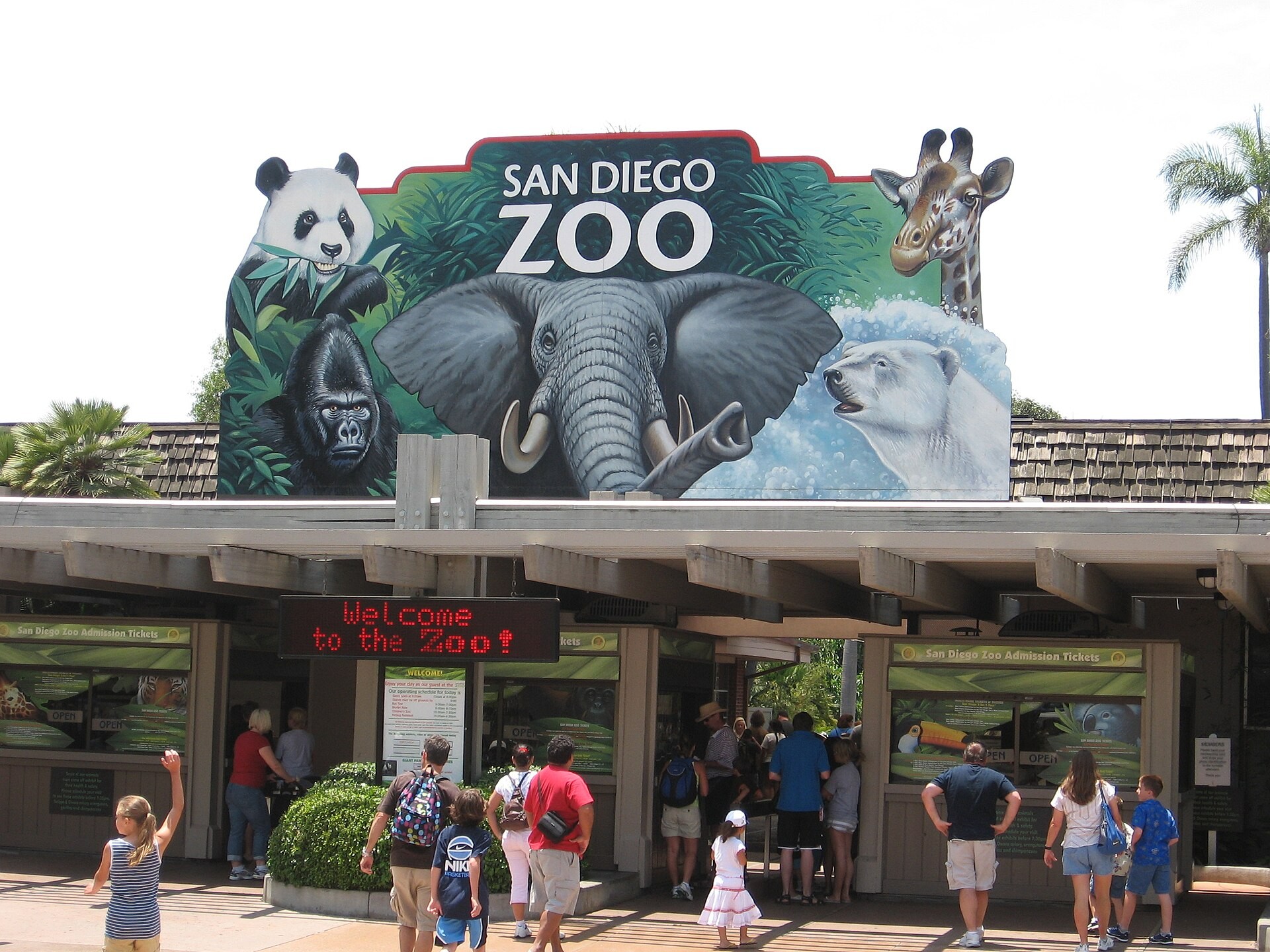 Main entrance of the San Diego Zoo with a painted animal mural above the ticket windows and visitors in front
