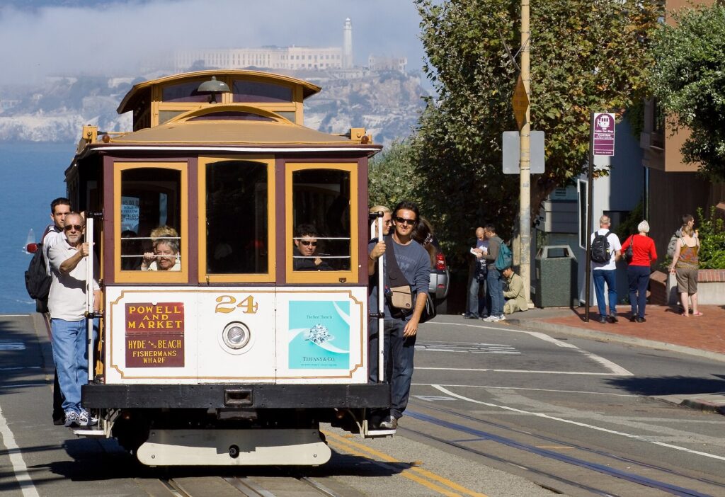 Powell-Hyde line cable car on a San Francisco hill with the bay behind it