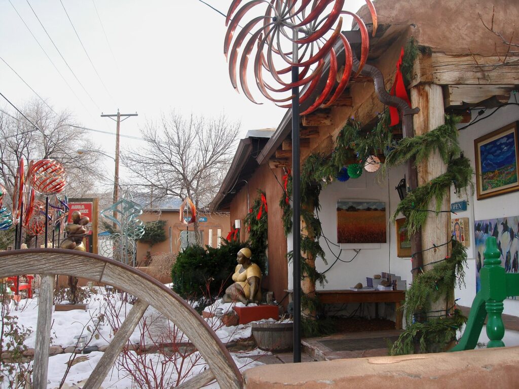A snow-dusted gallery courtyard with a wind sculpture on Canyon Road in Santa Fe, New Mexico