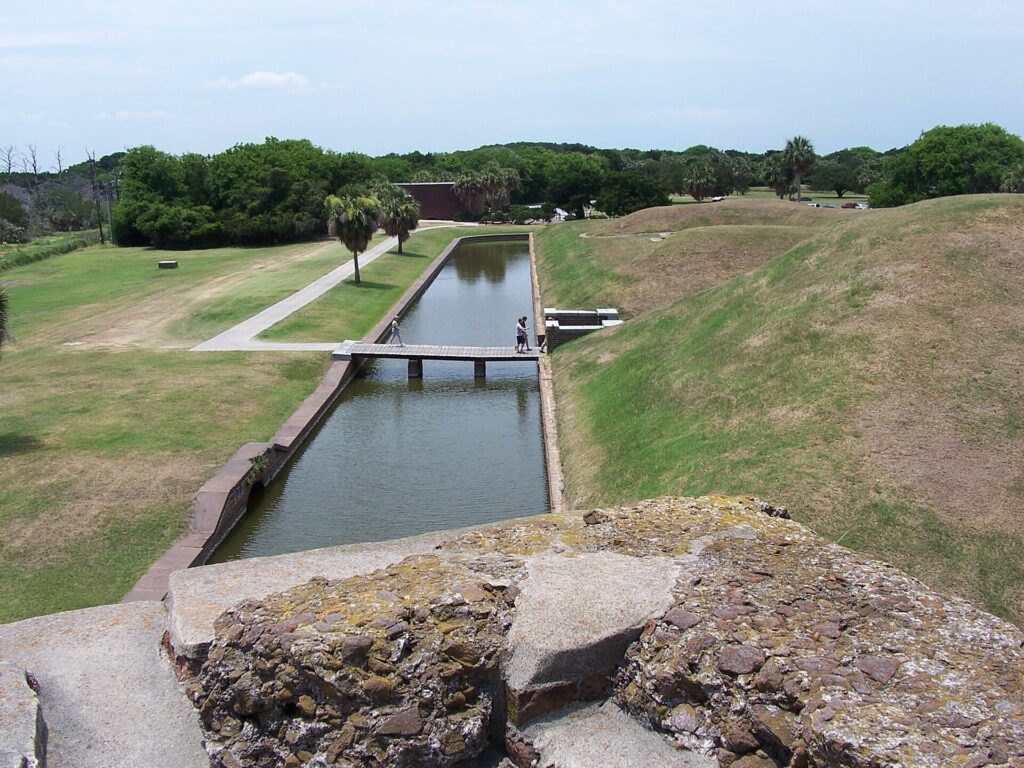 Moat with a footbridge and grass-covered ramparts at Fort Pulaski National Monument near Savannah