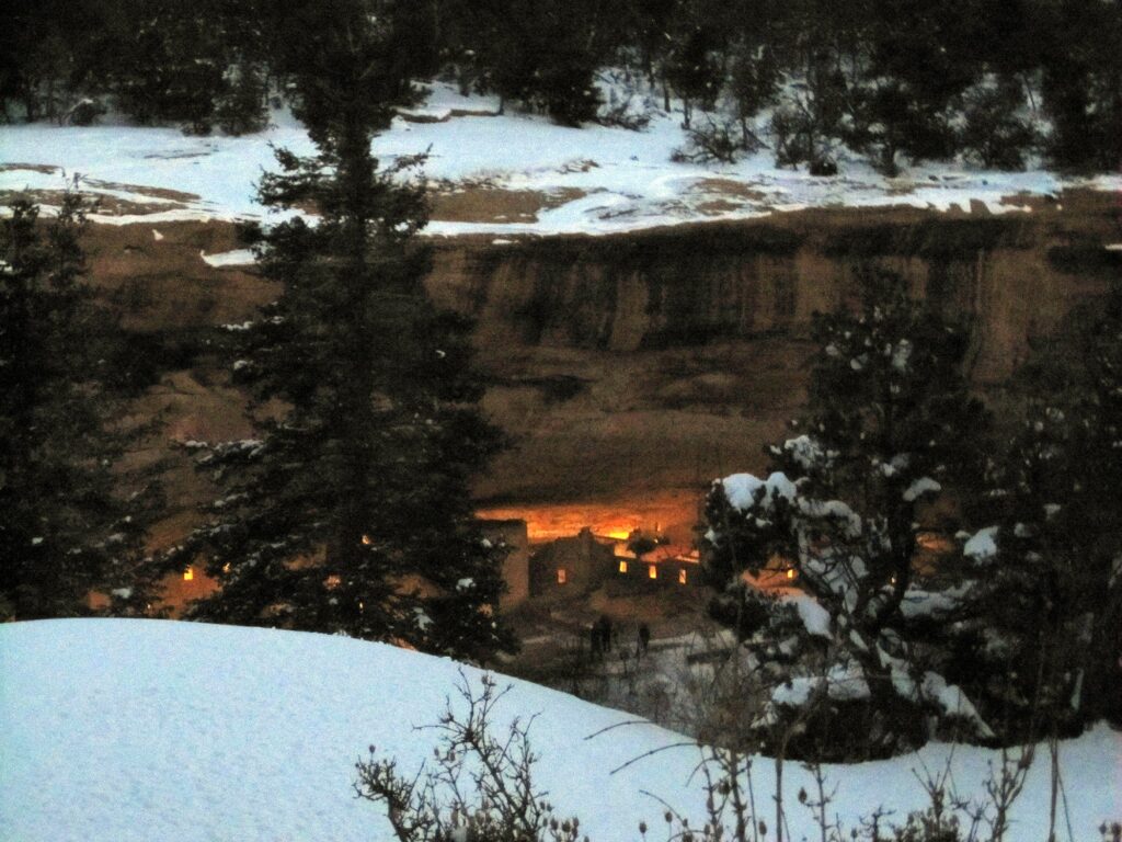 Snow on the canyon rim with Spruce Tree House glowing in its alcove at Mesa Verde National Park