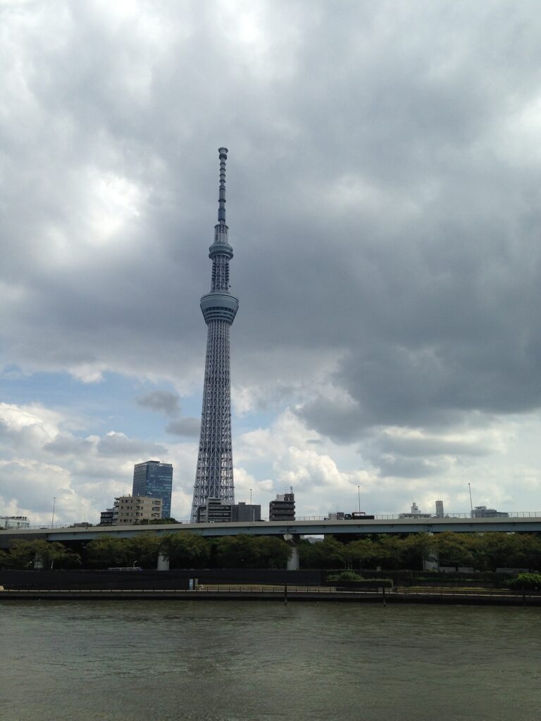Tokyo Skytree tower rising above the Sumida River under a cloudy sky