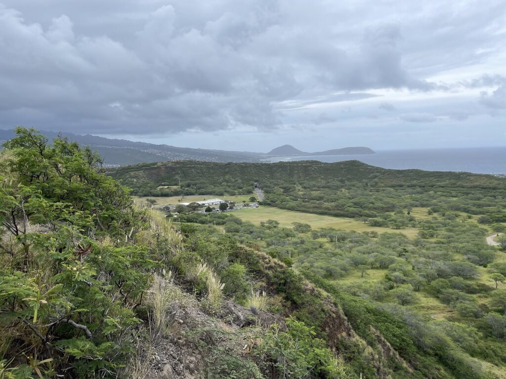 View over green slopes and the coast from the Diamond Head Summit Trail on Oahu