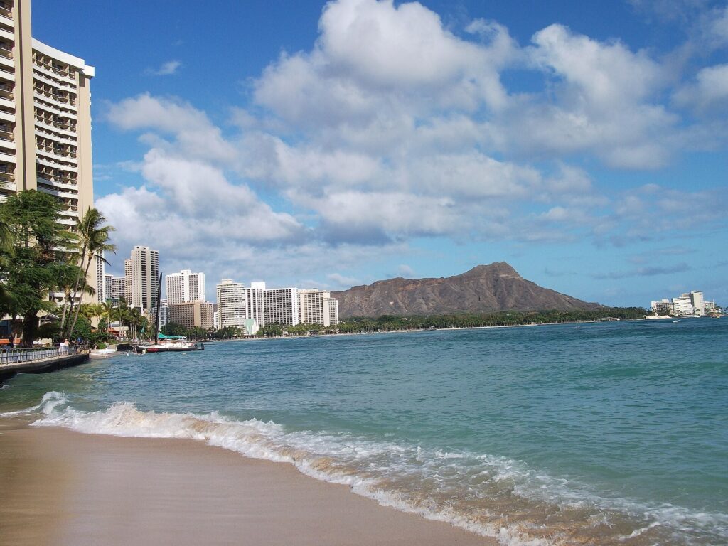 Waikiki Beach shoreline with gentle surf and Diamond Head rising behind the hotels