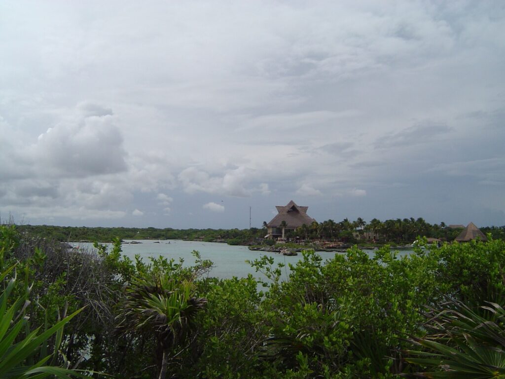 Calm inlet and mangroves with thatched buildings in the distance at Xel-Há park south of Cancun