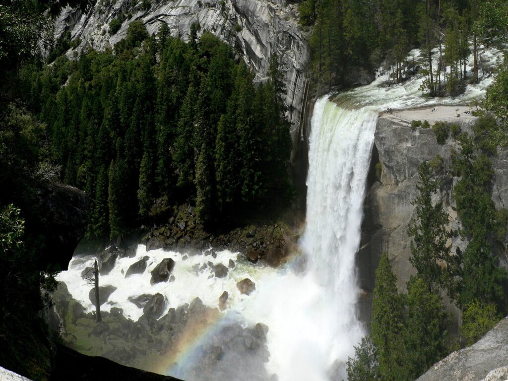 Vernal Fall dropping into a foaming pool with a rainbow at its base in Yosemite Valley