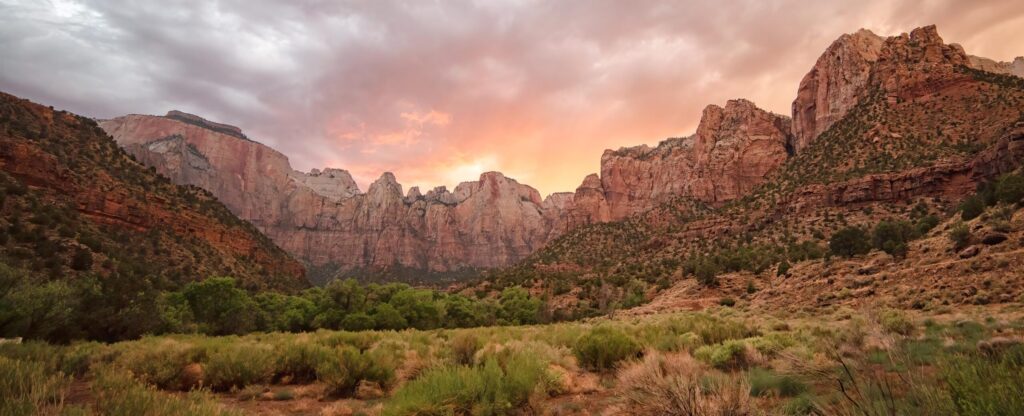 Towers of the Virgin rock peaks under a pink sunset sky in Zion National Park, Utah